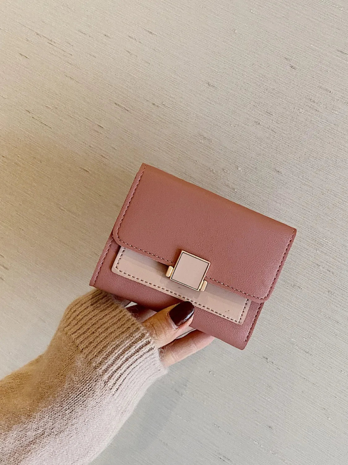 Pink wallet held by a hand against a light background