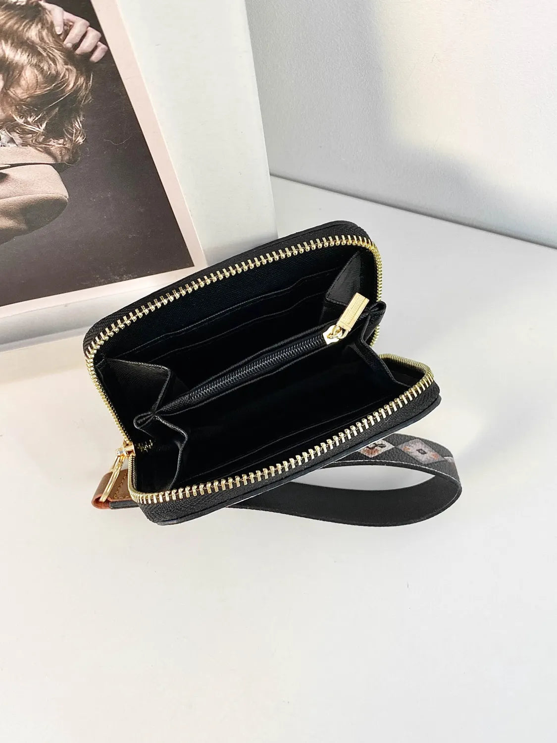 Black wallet with gold zipper on a white surface