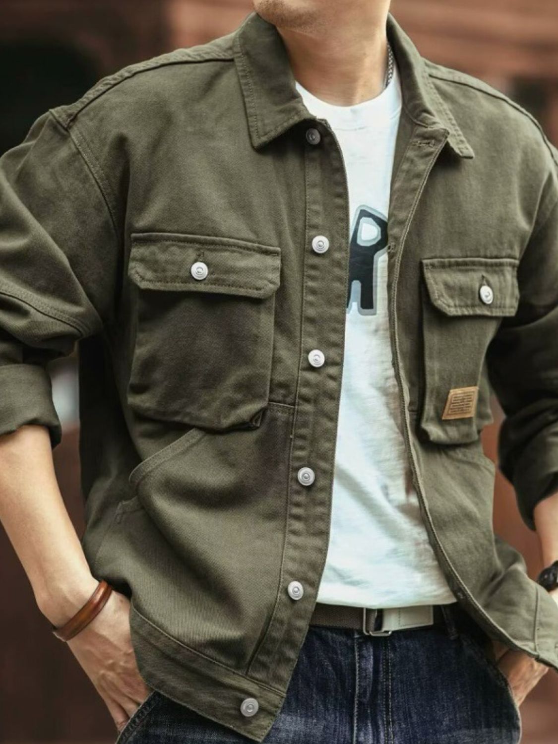 A man wearing a brown washed collared neck cargo jacket with button-up front and multiple pockets.