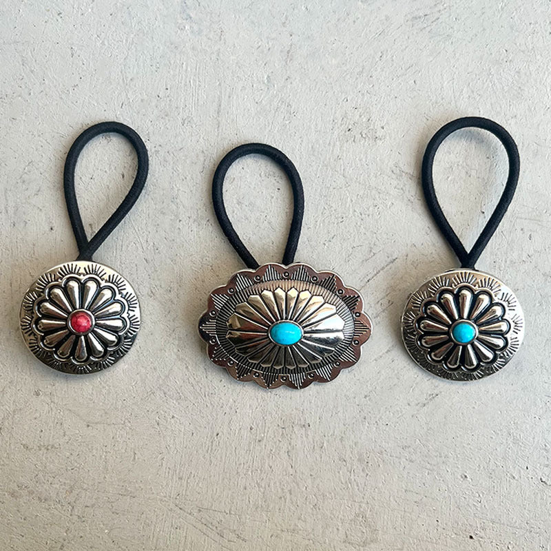 Three hair ties with decorative metal ends on a light gray background