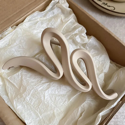 Decorative snake-shaped object on crumpled white paper inside a cardboard box.