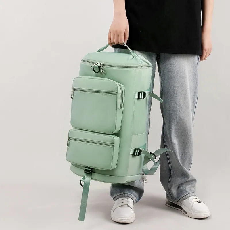 Person holding a mint green backpack with multiple compartments on a light gray background