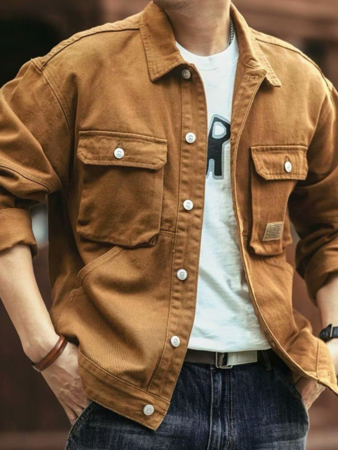 A man wearing a brown washed collared neck cargo jacket with button-up front and multiple pockets.