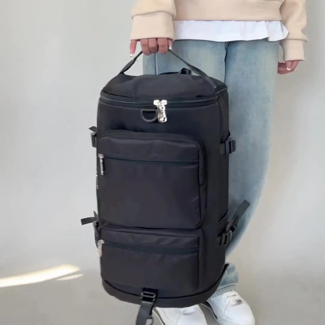 Person holding a black backpack against a plain background