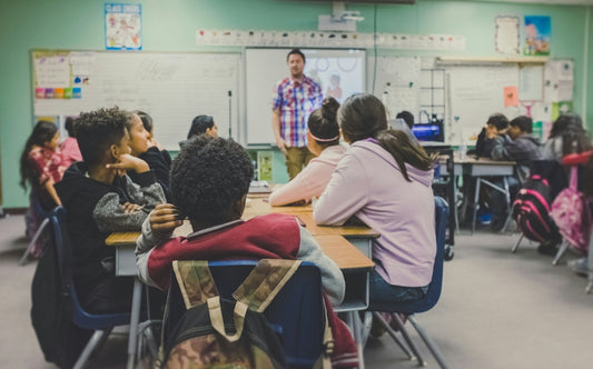 Students in a classroom listening to a teacher — back to school atmosphere