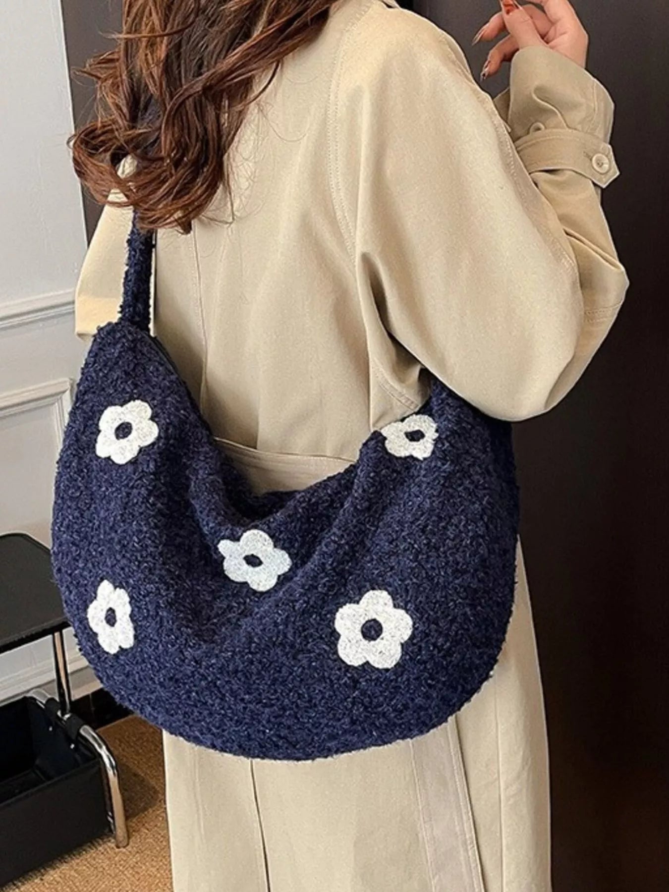 Person holding a navy blue bag with white floral patterns