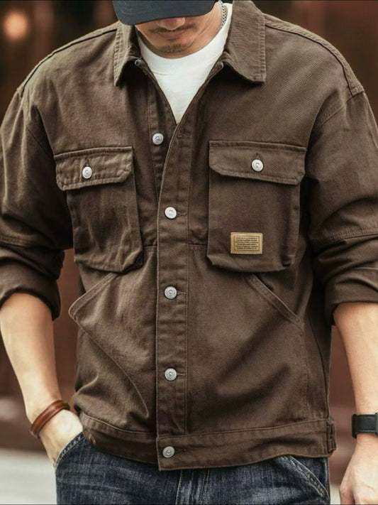 A man wearing a brown washed collared neck cargo jacket with button-up front and multiple pockets.