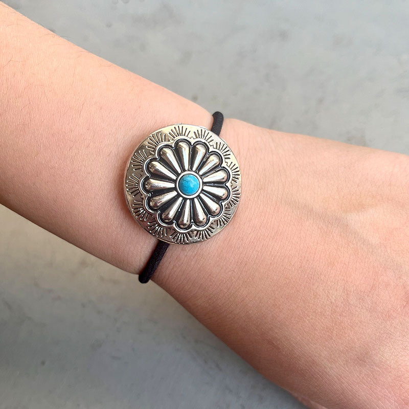 Silver bracelet with a blue stone on a wrist against a neutral background