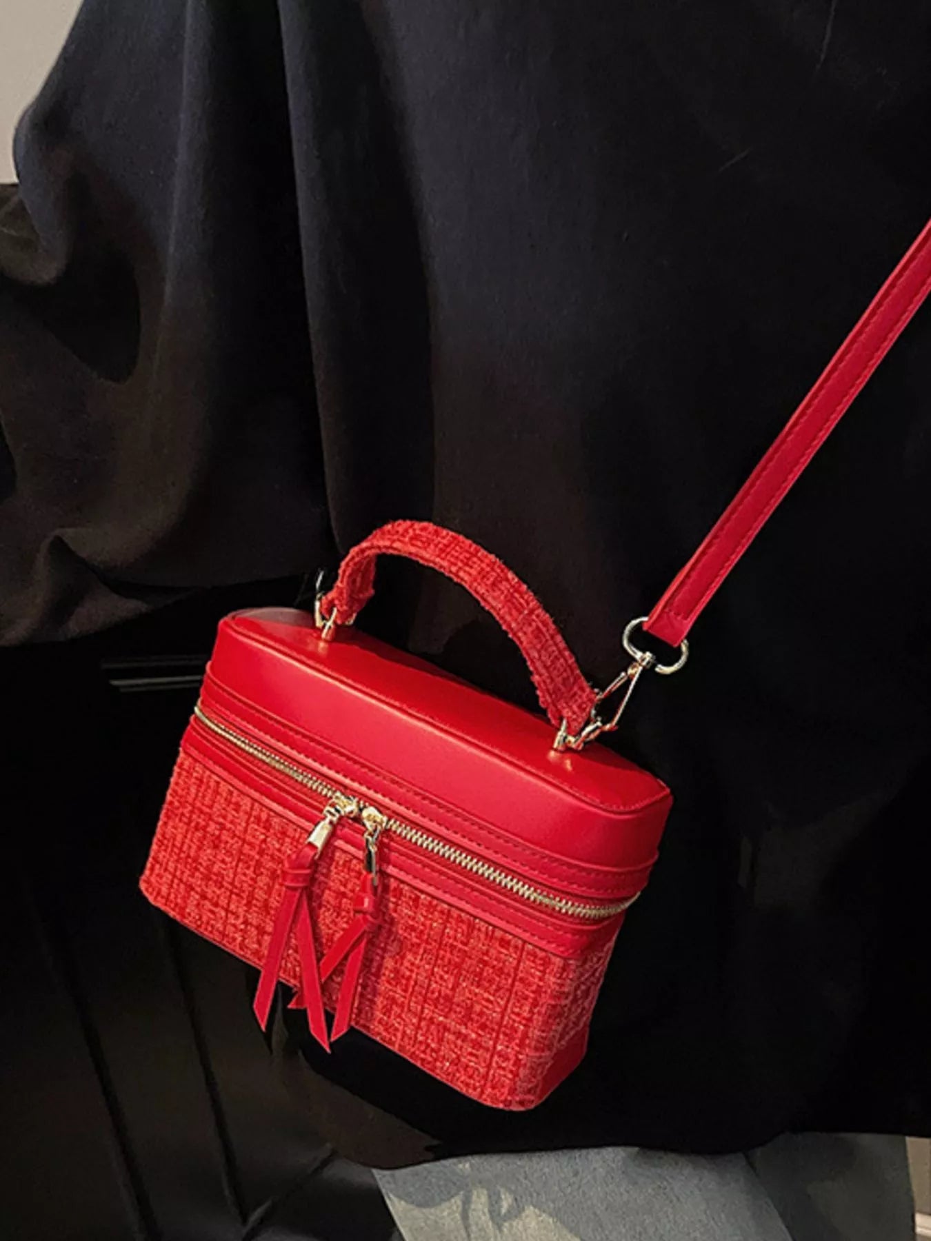 Red handbag with gold zipper on a black background