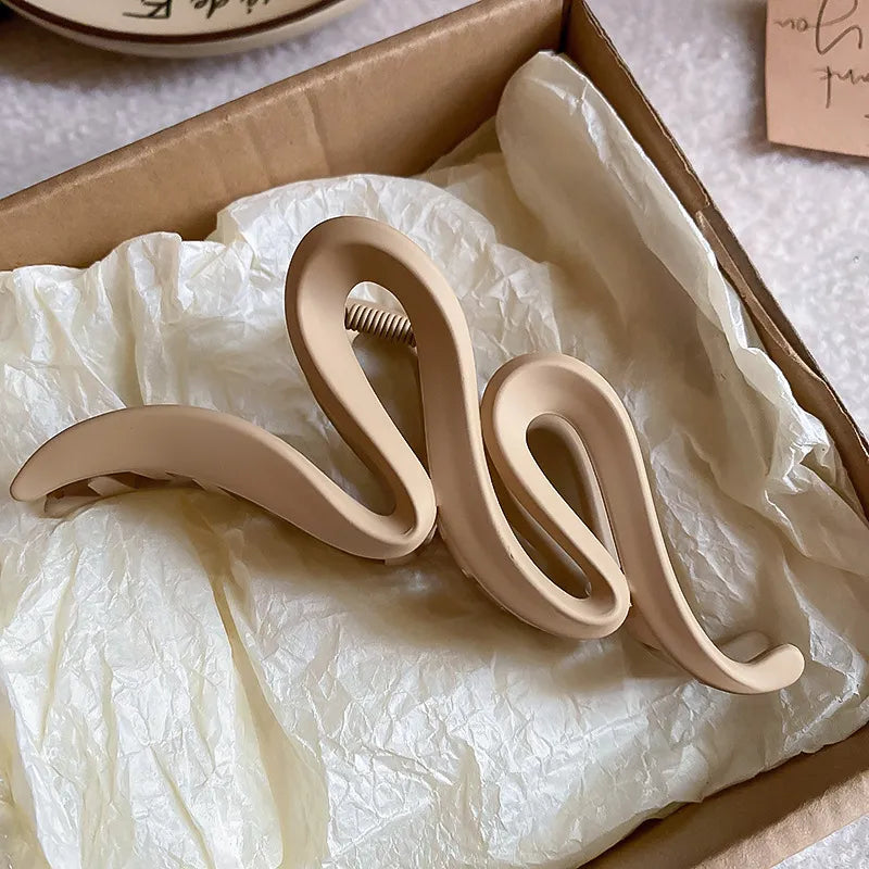 Decorative beige letter 'Q' on crumpled tissue paper inside a box.