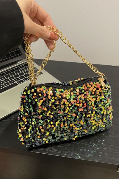 A small shoulder bag with a sequin embellished exterior and a gold-colored chain strap, displayed on a person's hand.