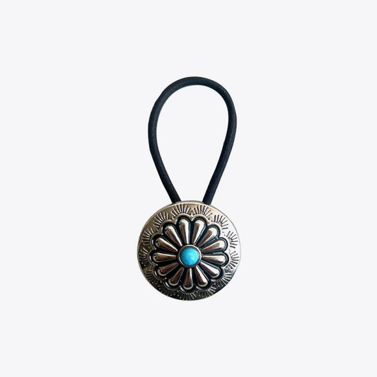 Decorative hair tie with a circular metal clasp and turquoise stone on a white background