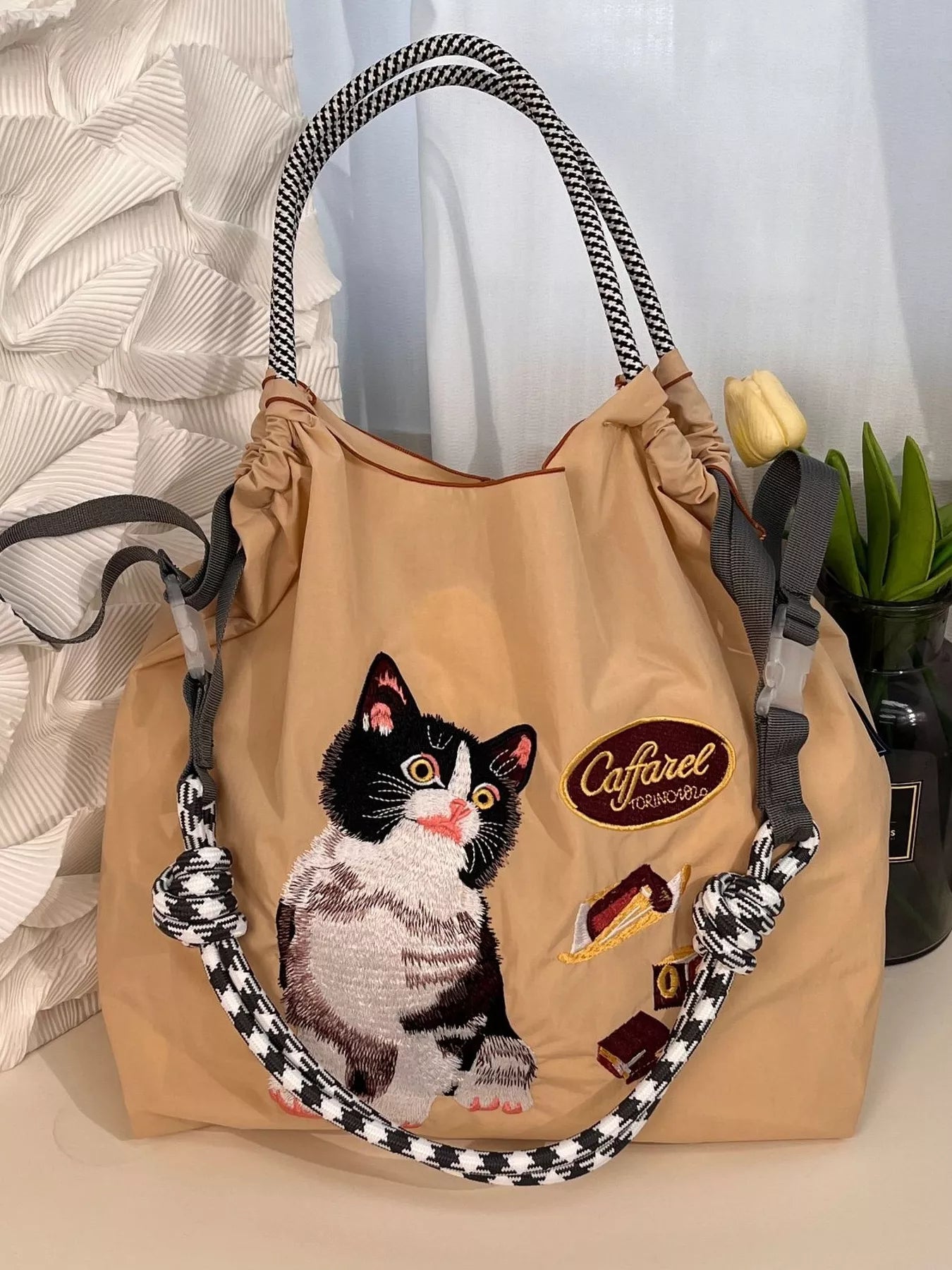Beige bag with a cat design and 'Cafarel' logo on a neutral background