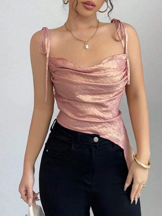 Woman wearing a pink metallic top and black pants against a gray background