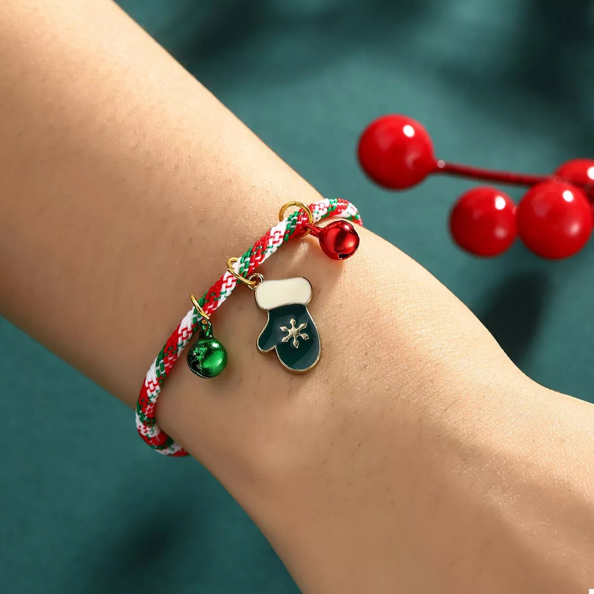 Bracelet with festive charms on a wrist against a teal background