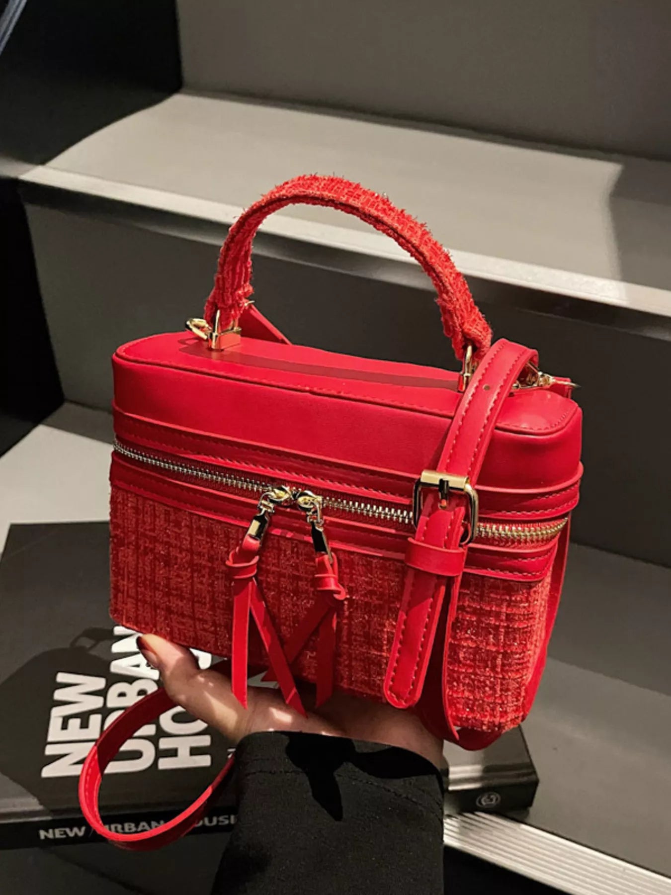 Red handbag with textured surface held by a person, with a blurred background