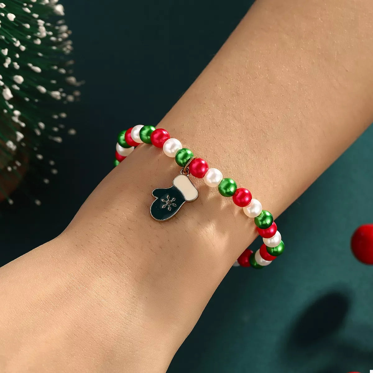Bracelet with red, green, and white beads on a wrist against a dark background