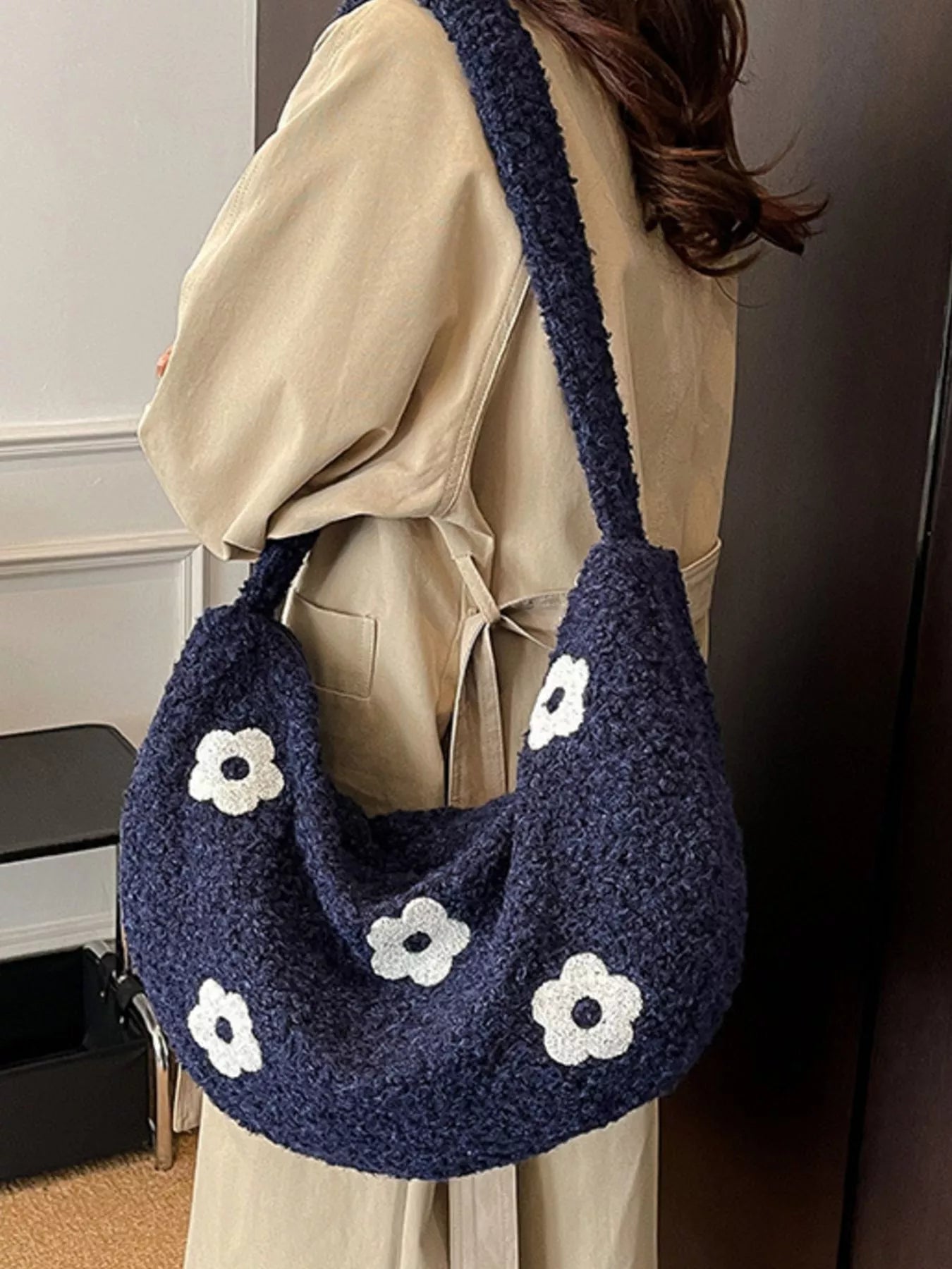 Navy blue handbag with white flower patterns worn by a person
