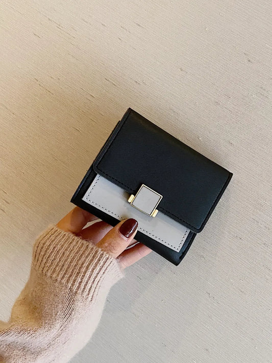 Black and white wallet held by a hand on a light wooden surface