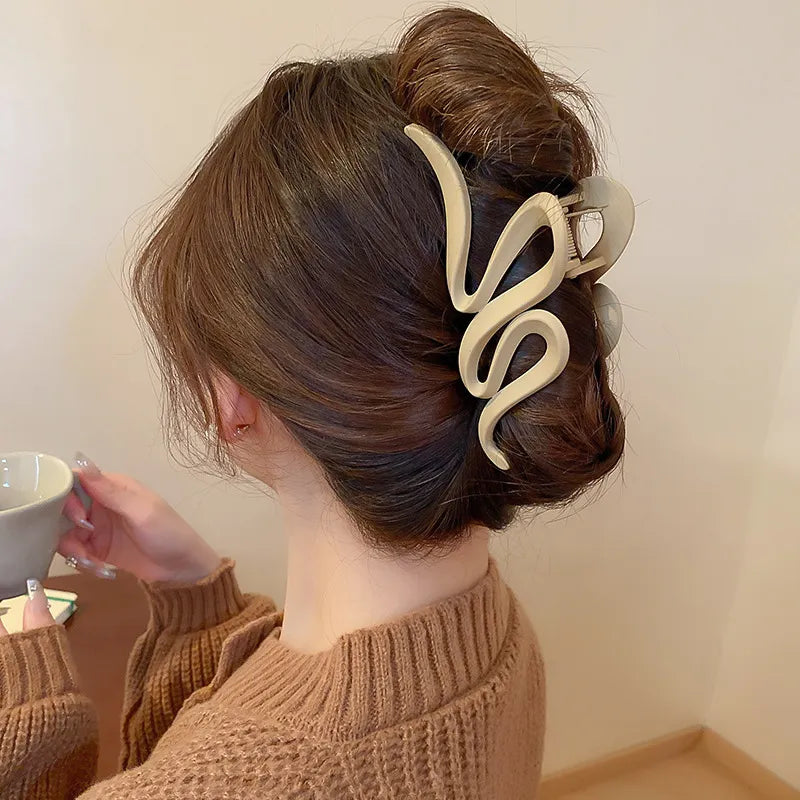 Person with a stylish hair accessory holding a cup against a plain background