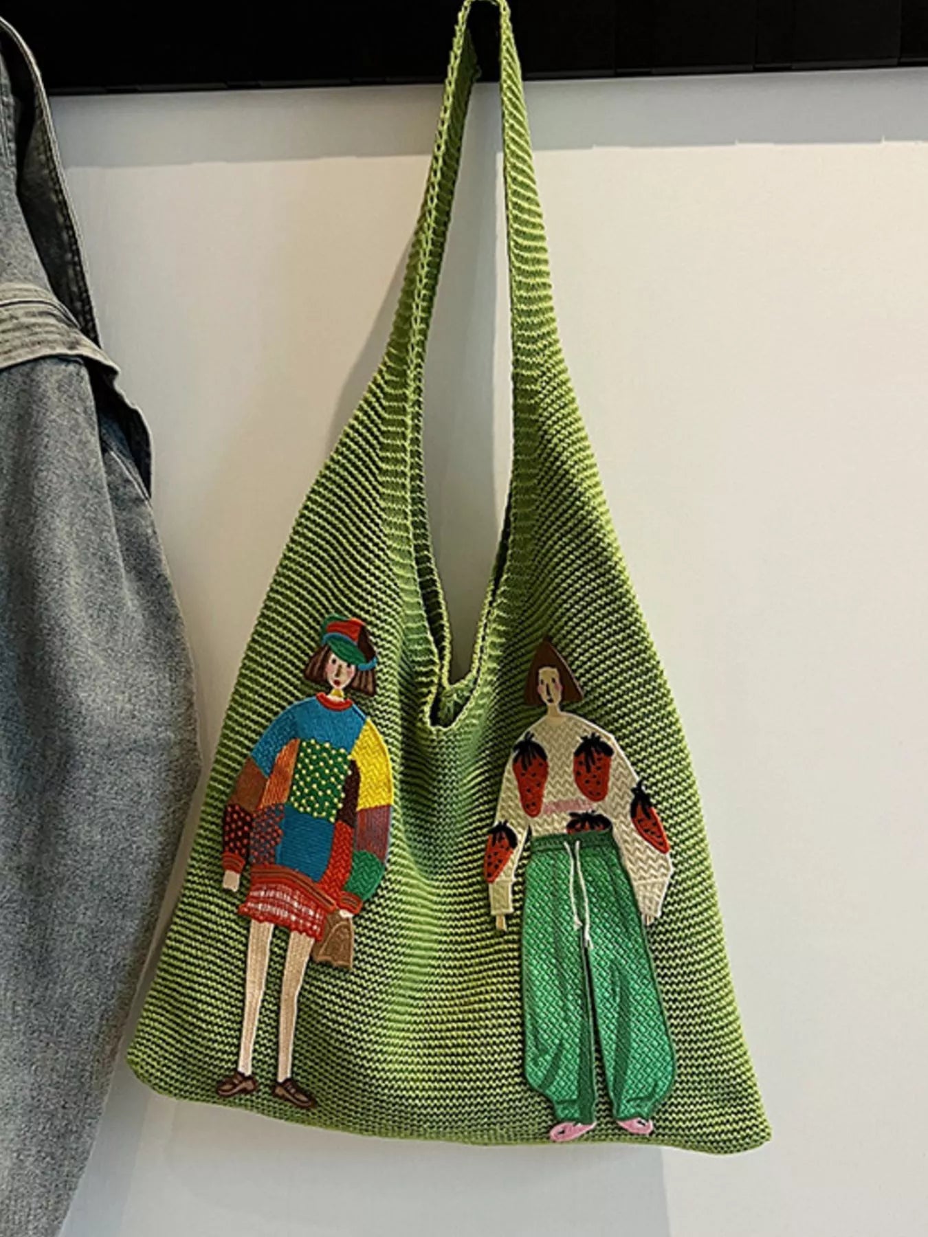 Green knitted bag with embroidered figures on a white background