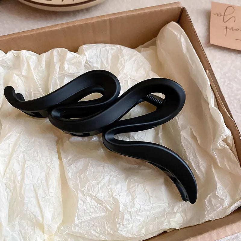 Black electronic device coiled up on crumpled white paper inside a cardboard box.