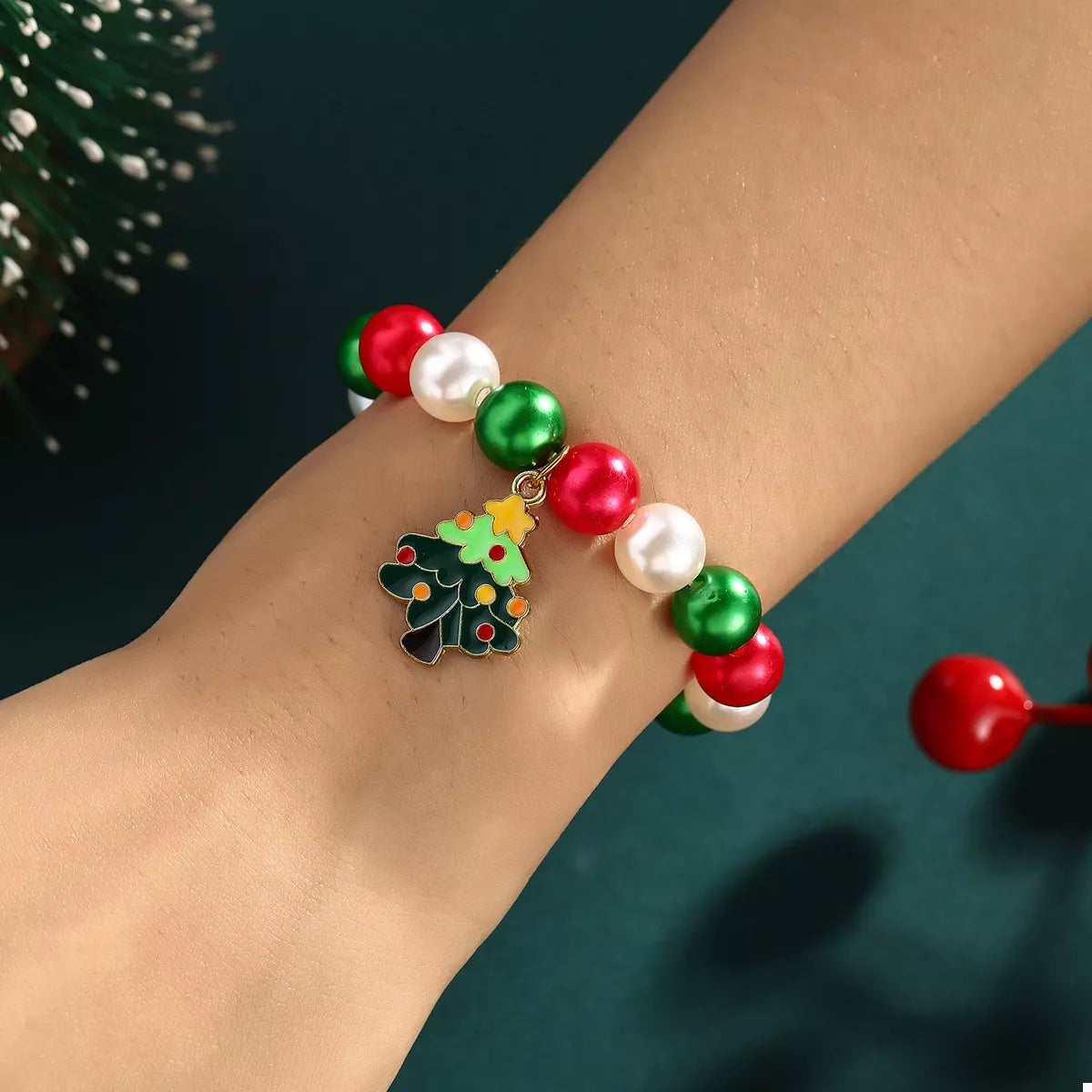 Colorful beaded bracelet with a Christmas tree charm on a wrist against a dark background