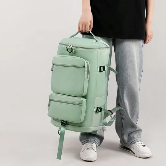 Person holding a mint green backpack with multiple compartments on a light gray background