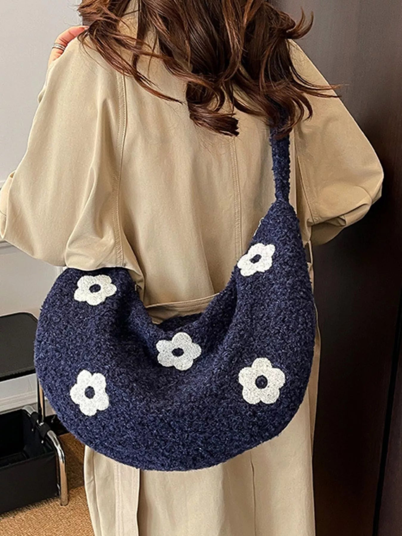 Person wearing a navy blue handbag with white floral patterns