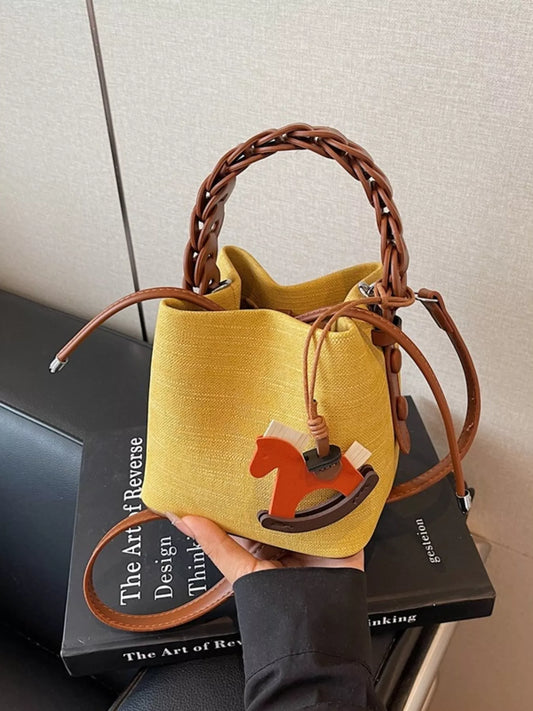 Yellow bucket bag with brown handle held over a book