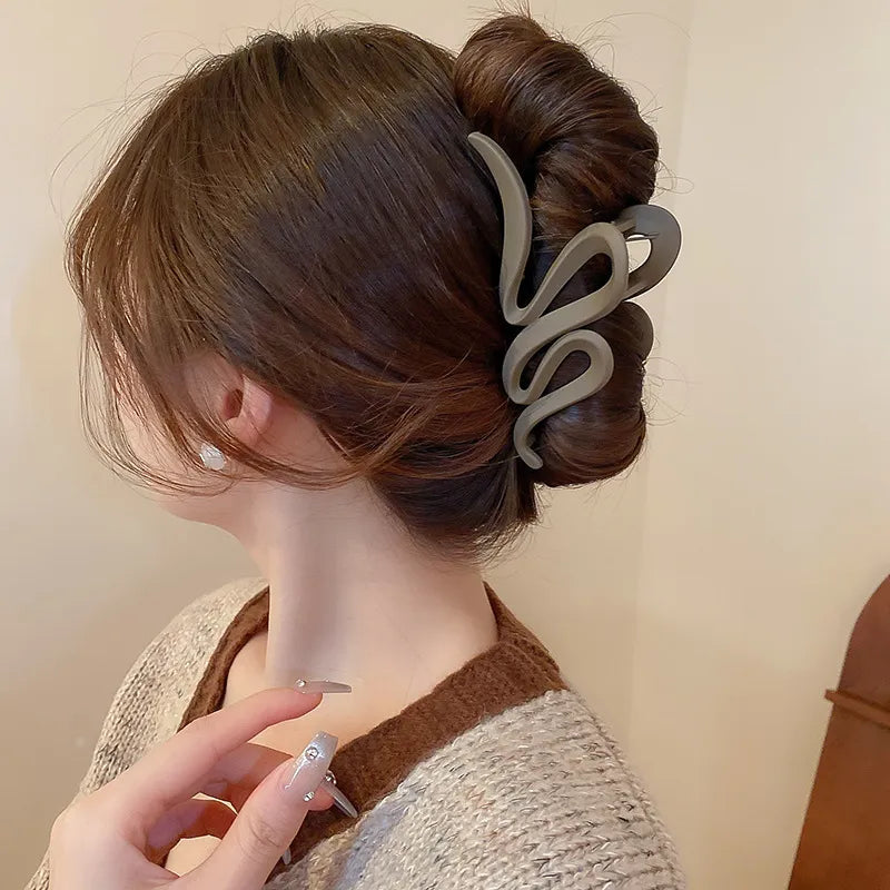 Person with a stylish hair bun held by a decorative hair clip against a neutral background