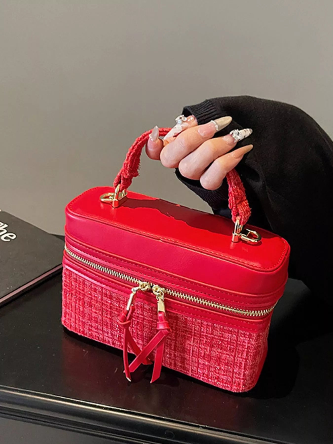 Red handbag with gold accents held by a person wearing a black glove.