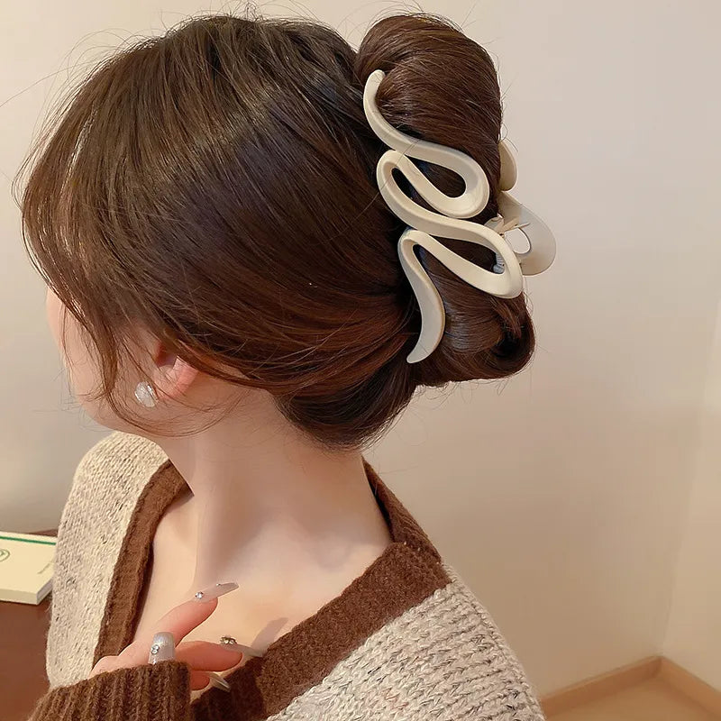 Woman with brown hair styled in an updo using a white hair tie against a neutral background