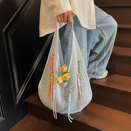 Person holding a white woven bag with decorative elements on a wooden staircase.